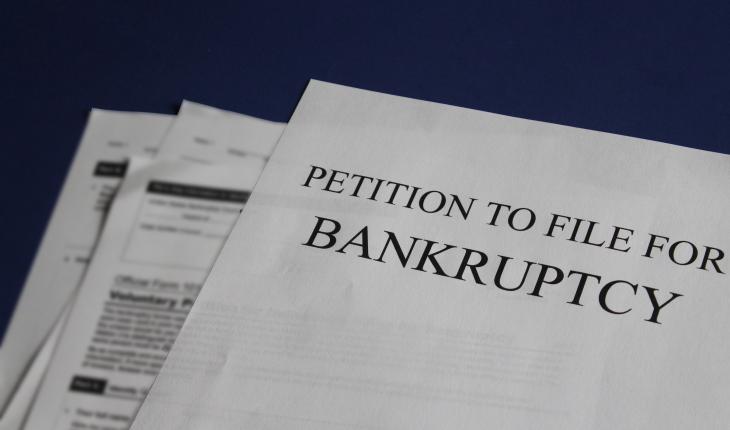 printed newspaper with article about a petition to file for bankruptcy